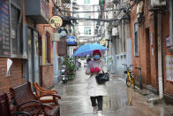 A resident wearing a face mask to help protect against COVID-19 walks along a narrow street in Wuhan in central China's Hubei Province, Sunday, Jan. 23, 2022. Sunday will mark two years since the city of Wuhan was placed under a 76-day lockdown as China tried to contain the first major outbreak of the coronavirus pandemic. (AP Photo)