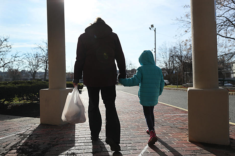 BOSTON - DECEMBER 11: A woman and her daughter walk from  her elementary school after picking  up her breakfast and lunch in Revere, MA on Dec. 11, 2020. She is among many low-income parents in Massachusetts who have struggled to receive their promised free school meals during the pandemic. Her daughter's school offers meal pick-up from 10:30a.m. to 1 p.m., but her daughter only has a break from classes from 10:50 to 11:30, and so the single mother must strap her daughter in a jogging stroller and rush to the school a half-mile away since they don't have a car to pick up meals. (Photo by Suzanne Kreiter/The Boston Globe via Getty Images)
