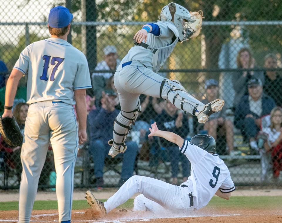 McKeel's Brody Lanier slides safely into home as Lakeland Christian catcher Mitch Rodrigues jumps to make the catch on Friday in the championship game of the Polk County Baseball Tournament.