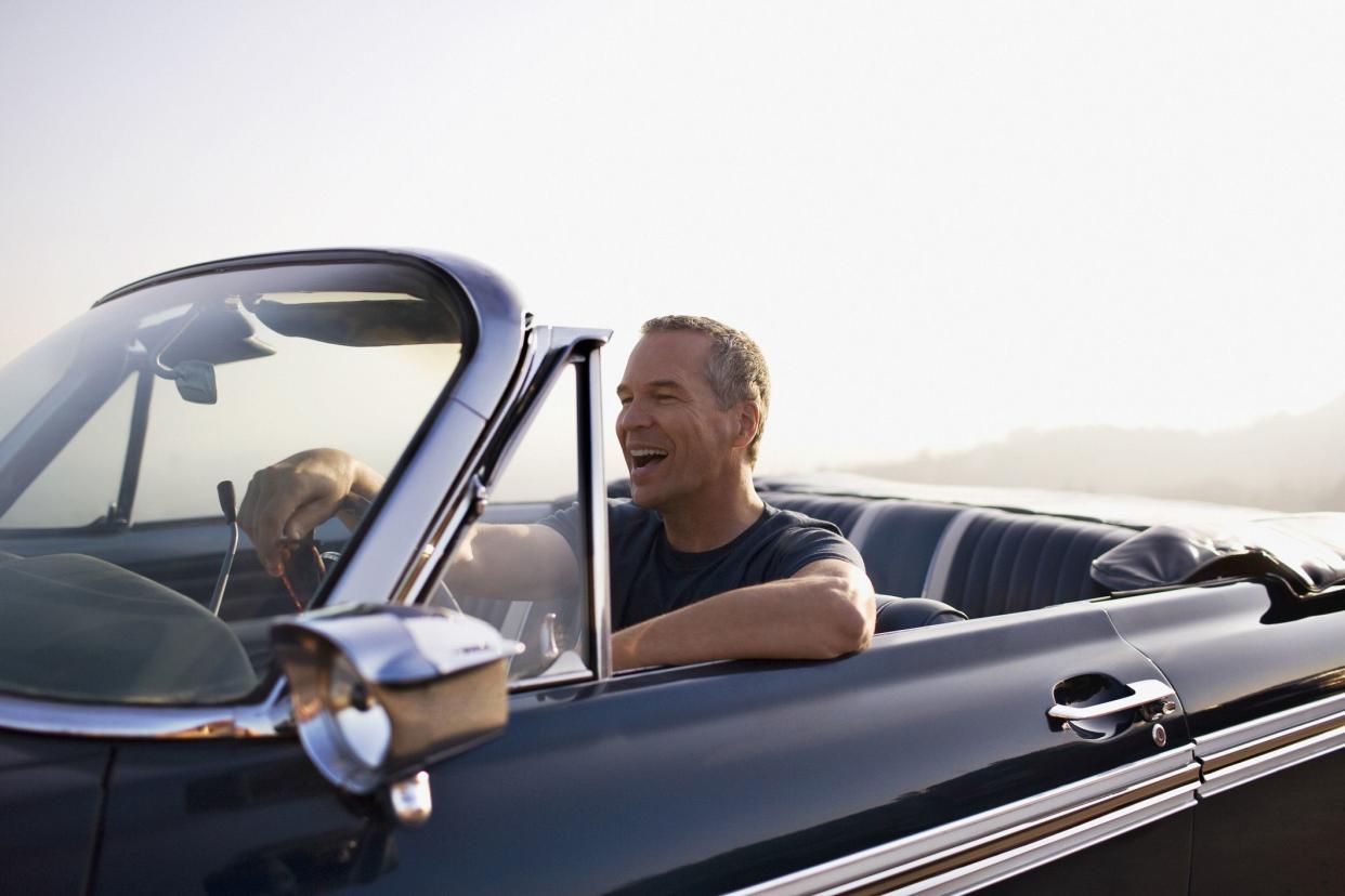 happy middle-aged man driving convertible