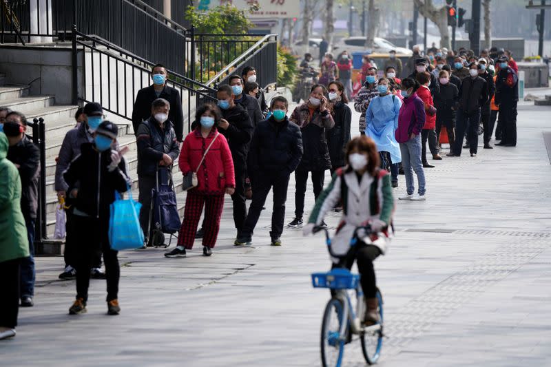 People wearing face masks line up to enter a supermarket in Wuhan