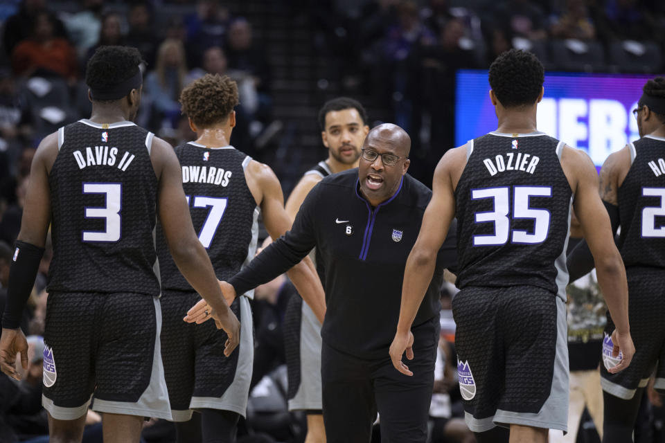 Sacramento Kings coach Mike Brown greets guard Terence Davis (3) and guard PJ Dozier (35) during a timeout in the first half of the team's NBA basketball game against the Golden State Warriors in Sacramento, Calif., Friday, April 7, 2023. (AP Photo/José Luis Villegas)