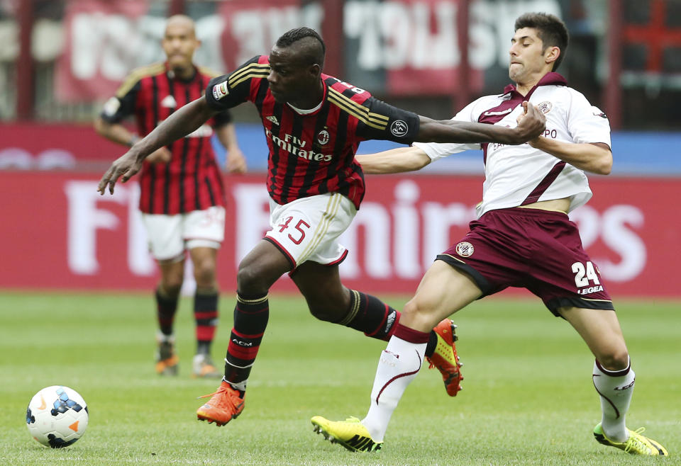 AC Milan forward Mario Balotelli, left, challenges for the ball with Livorno midfielder Marco Benassi during a Serie A soccer match at the San Siro stadium in Milan, Italy, Saturday, April 19, 2014. (AP Photo/Antonio Calanni)