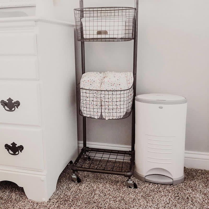 White diaper pail next to wire rack and white dresser