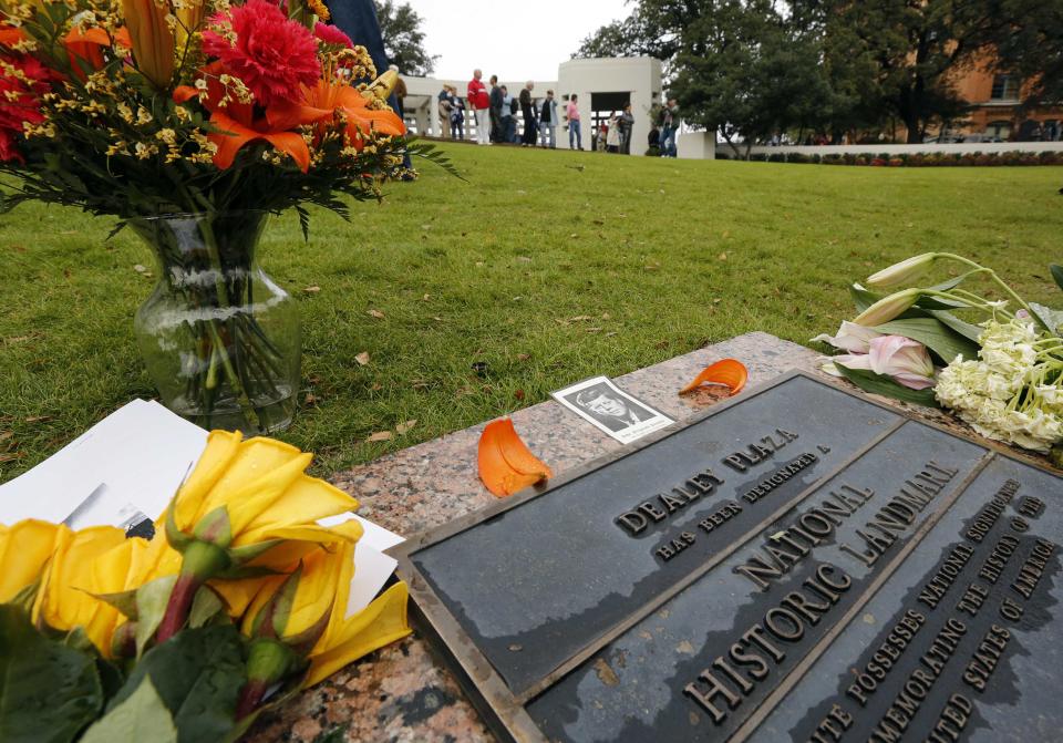 Fresh flowers and the Roman Catholic Mass card from President John F. Kennedy's funeral sit atop the plaque declaring Dallas's Dealey Plaza a National Historic landmark in Dallas