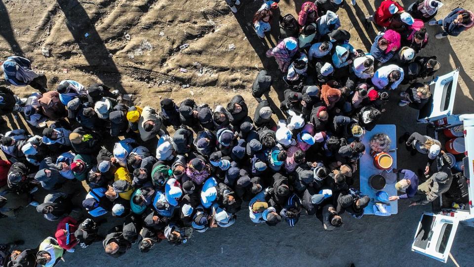 Migrants gather around a truck delivering hot food.