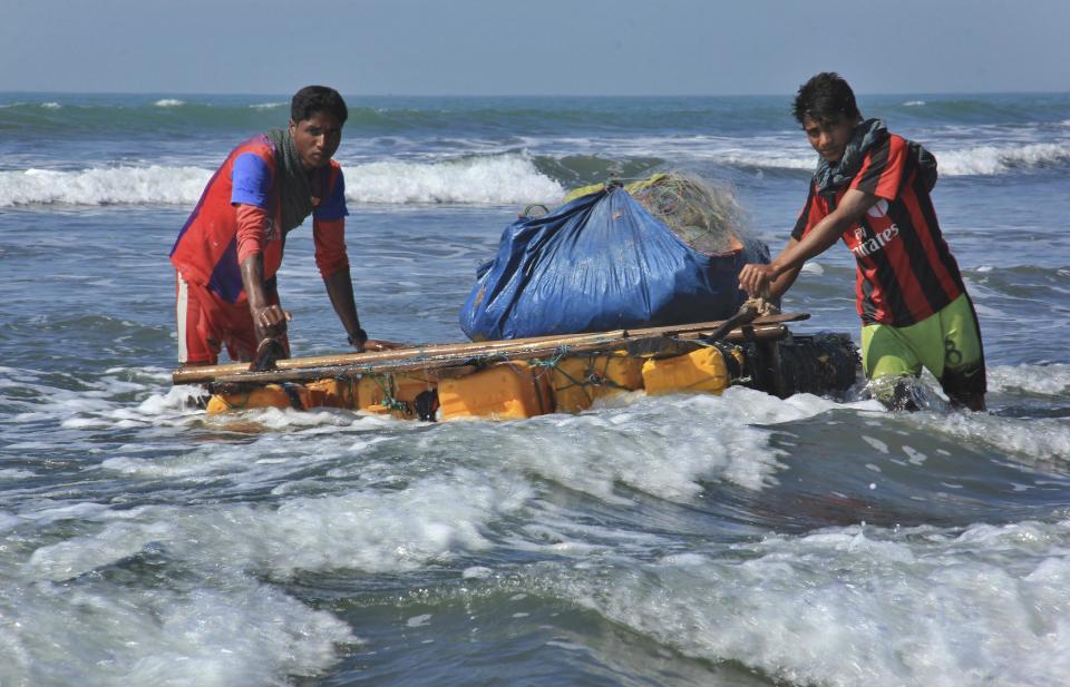 In this Jan. 16, 2017, photo, Rohingya fishermen pull their raft made of empty plastic containers along the coastline of the Bay of Bengal in Tha Pyay Taw village, Maungdaw, western Rakhine state, Myanmar. Their usual, sturdy fishing boats were outlawed three months ago when Myanmar authorities launched a sweeping and violent counter-insurgency campaign in Rakhine state, home to the long-persecuted Rohingya Muslim minority. The ban on fishing boats _ meant to prevent insurgents from entering or leaving the country by sea _ is just one small provision in the wider crackdown, in which authorities have been accused of widespread abuses. (AP Photo/Esther Htusan)