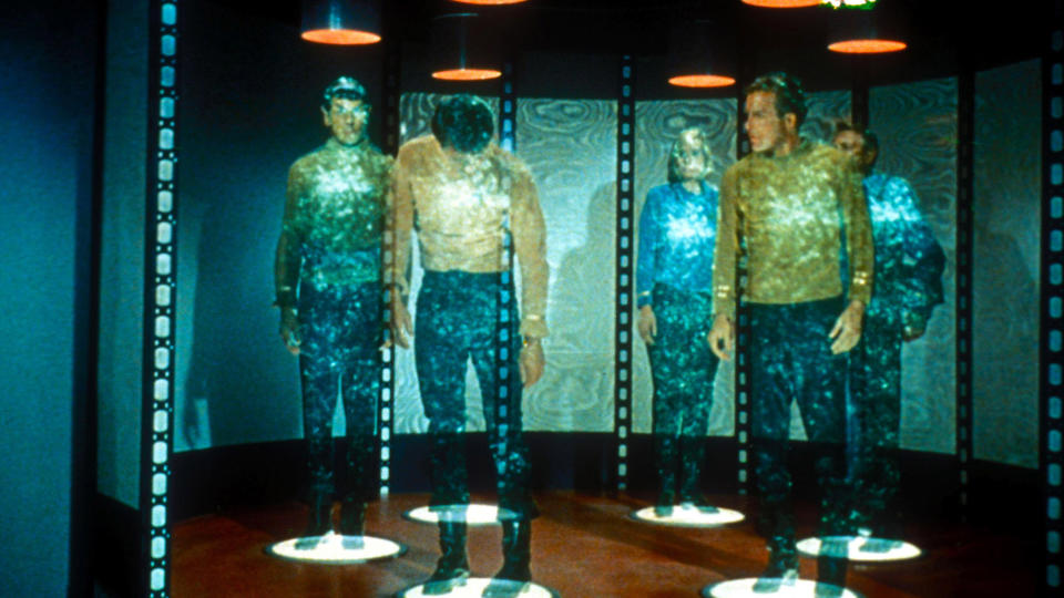 Captain Kirk and other crew members in a transporter room in the original Star Trek.