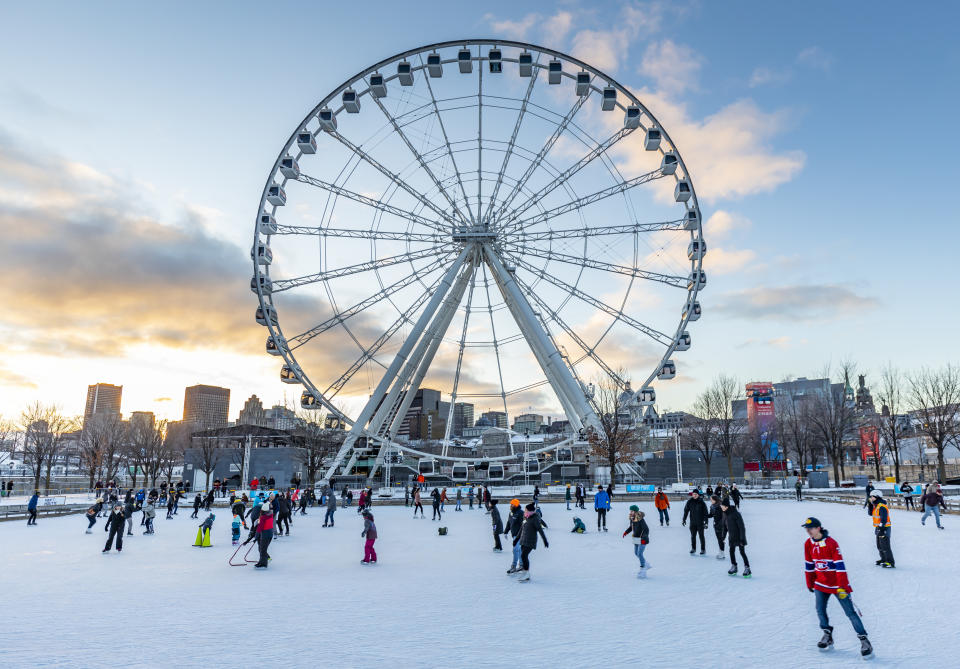 Skaters and families enjoying the ice rink in front of La Grande Roue de Montréal on a sunny winter day