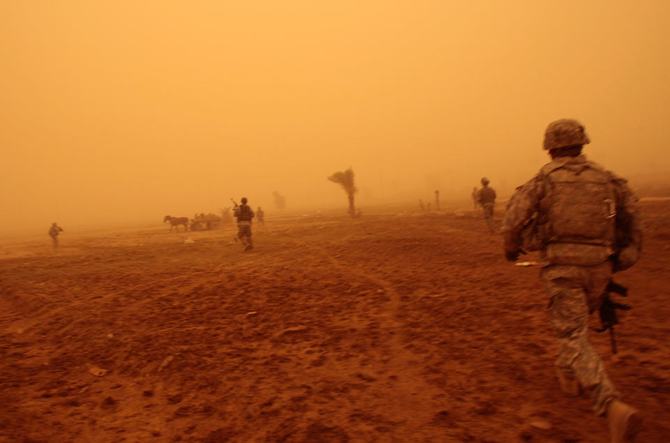 <p>In the orange fog of an Iraqi sandstorm, US troops run up and fire warning shots at three Iraqi men in a field who started running from their patrol May 16, 2008 in Baghdad, Iraq. One of the three men was shot in the leg by the advancing US troops, and started bleeding heavily. He was immediately treated by the US medic traveling with the platoon and transported to the nearest US base for medical care, and is expected to recover. The other two men were arrested by the troops and brought in for investigation. (Photo by Chris Hondros/Getty Images) </p>