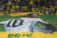 Brazilian fans hold a banner showing the Brazilian soccer legend Pele with the message 'Get well soon' during the World Cup round of 16 soccer match between Brazil and South Korea at the Stadium 974 in Doha, Qatar, Monday, Dec. 5, 2022. Pele is in a hospital in San Paulo recovering from a respiratory infection. (AP Photo/Jin-Man Lee)