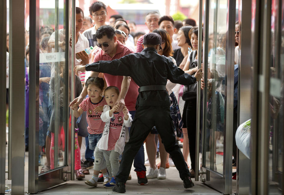 <p>A security guard opens the entrance doors for the grand opening of the Wanda Mall at the Wanda Cultural Tourism City in Nanchang in southeastern China’s Jiangxi province, May 28, 2016. China’s largest private property developer, the Wanda Group, opened an entertainment complex on Saturday that it’s positioning as a distinctly homegrown rival to Disney and its $5.5 billion Shanghai theme park opening next month. (AP Photo/Mark Schiefelbein) </p>