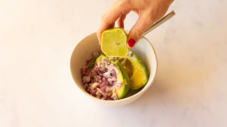 hand squeezing lime juice into guacamole