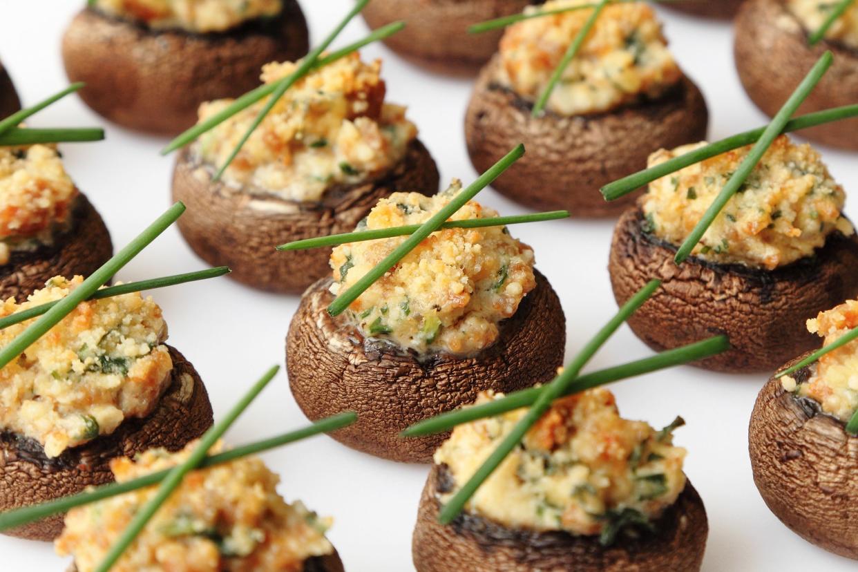 Closeup of rows of several easy stuffed mushrooms on a white plate