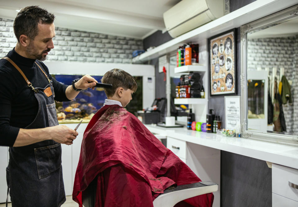 A barber cutting a young boy's hair