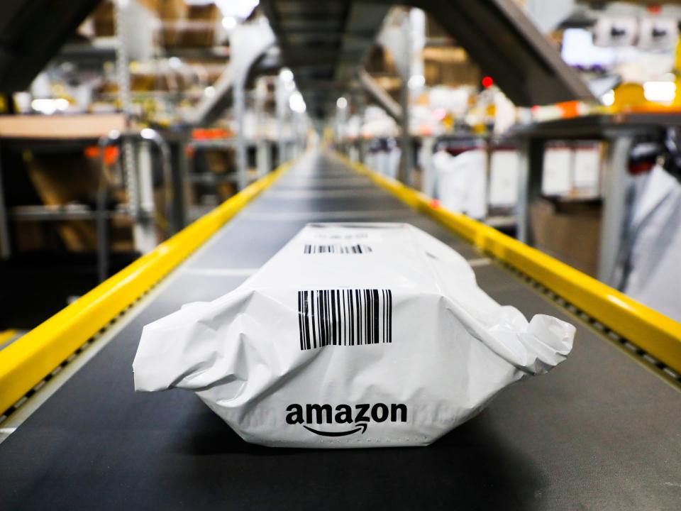 A white Amazon package with a black barcode on a conveyor belt