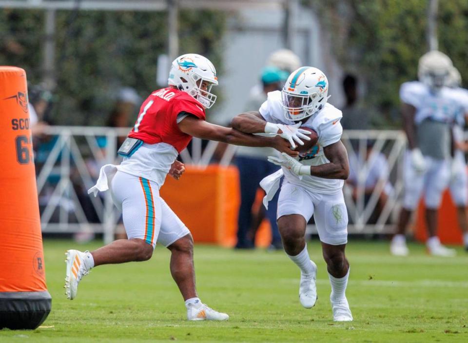 El quarterback de los Dolphins Tua Tagovailoa le pasa el ovoide al running back ZaQuandre White en una jugda durante la práctica del equipo celebrada en el Baptist Health Training Complex en el Hard Rock Stadium, en Miami Gardens, Florida, el 7 de agosto de 2022.