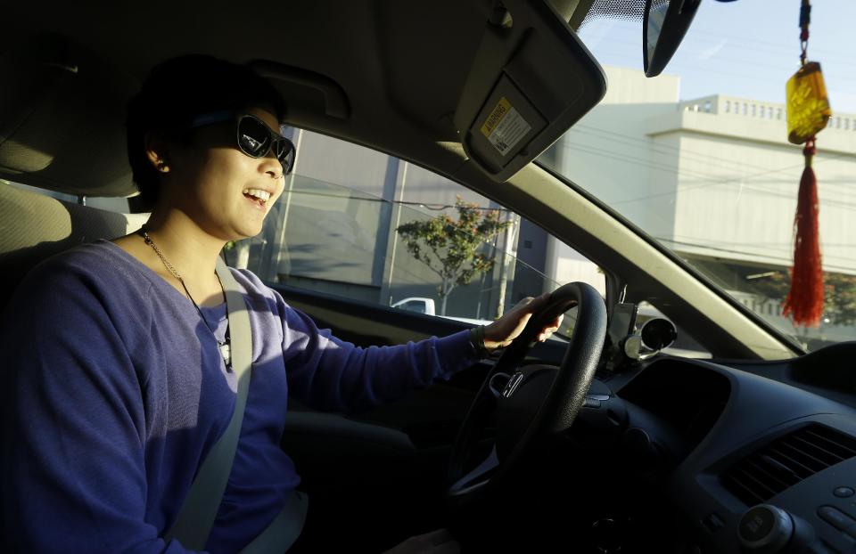 In this Jan. 4, 2013 photo, Lyft driver Nancy Tcheou smiles as she drives in San Francisco. Fed up with traditional taxis, city dwellers are tapping their smartphones to hitch rides from strangers using mobile apps that allow riders and drivers to find each other. Internet-enabled ridesharing services such as Lyft, Uber and Sidecar are expanding rapidly in San Francisco, New York and other U.S. cities, billing themselves as a high-tech, low-cost alternative to cabs. (AP Photo/Jeff Chiu)