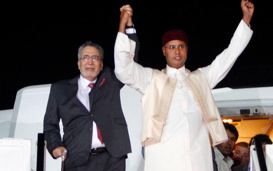Libyan Abdel Baset al-Megrahi, who was found guilty of the 1988 Lockerbie bombing, left, and son of the Libyan leader Saif al-Islam Gadgafi, right, gesture on his arrival at an airport in Tripoli, Libya. - Credit: AP