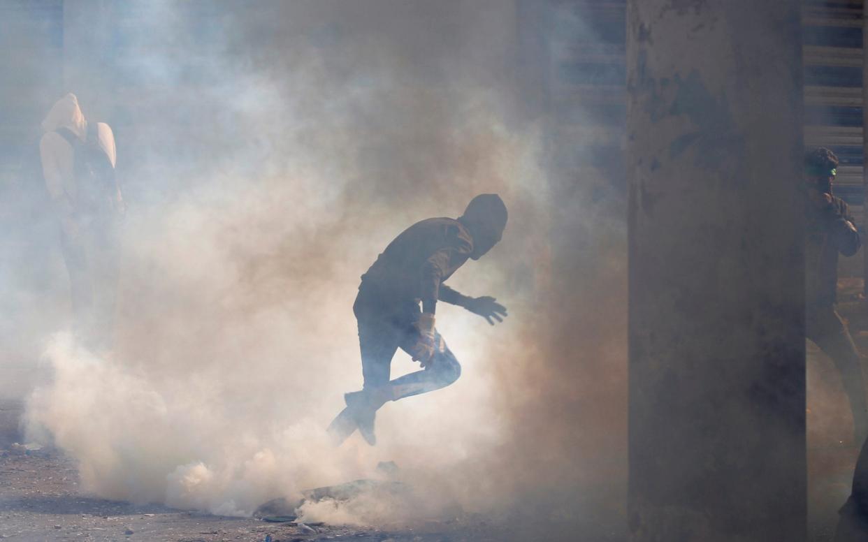 A demonstrator runs away from tear gas during  anti-government protests in Baghdad on November 24, 2019 - REUTERS
