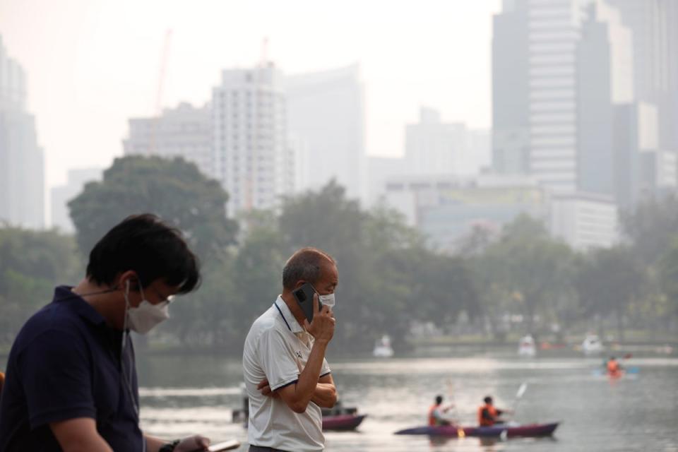 People wear face masks as high-rise buildings are shrouded in smog and haze from heavy fine dust at Lumpini Park in Bangkok (EPA)