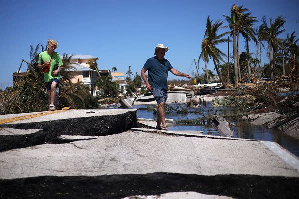 MATLACHA, FLORIDA - SEPTEMBER 30: Pine Island residents Wolfgang Nester (R) and his son Sebastian walk amongst the wreckage lef in the wake of Hurricane Ian on the island of Matlacha on September 30, 2022 in Matlacha, Florida. The hurricane brought high winds, storm surge and rain to the area causing severe damage. (Photo by Win McNamee/Getty Images)