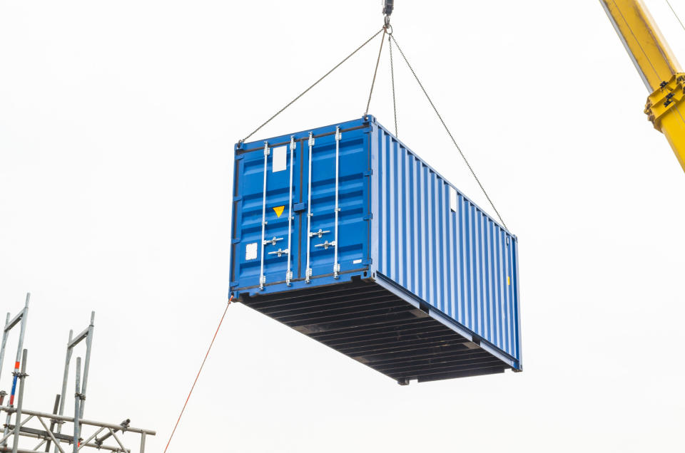 A typical shipping container being held up by a crane