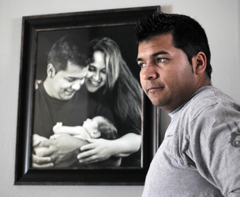 FILE - In this Friday, Jan. 3, 2014 file photo, Erick Munoz stands with an undated copy of a photograph of himself, left, with wife Marlise and their son Mateo, in Haltom City, Texas. John Peter Smith Hospital in Fort Worth, issued a statement Sunday, Jan. 26, 2014 that said the hospital it will remove life support from Marlise Munoz, following a judge’s order that it was misapplying state law to disregard her family’s wishes. The statement did not say when the hospital would pull life support. (AP Photo/The Fort Worth Star-Telegram, Ron T. Ennis, File) MANDATORY CREDIT