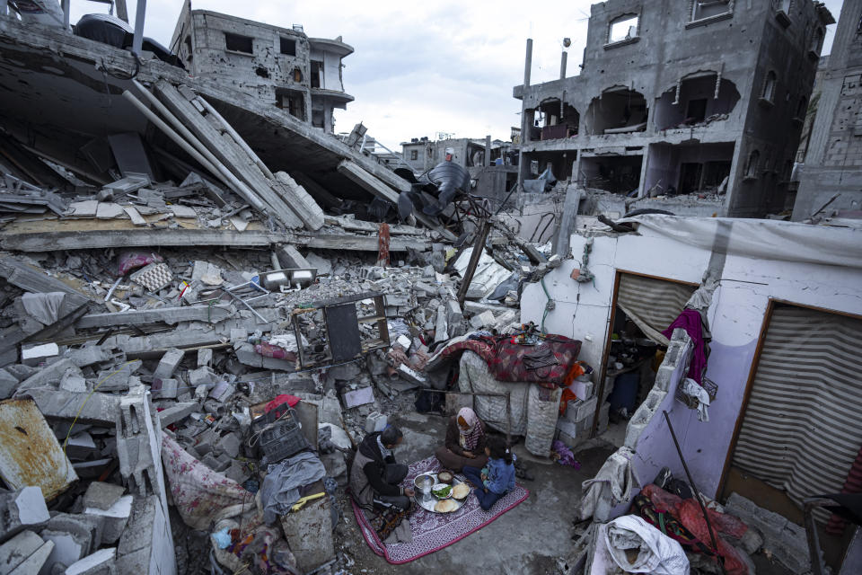 Members of the Al-Rabaya family break their fast during the Muslim holy month of Ramadan outside their destroyed home by the Israeli airstrikes in Rafah, Gaza Strip, Monday, March 18, 2024. (AP Photo/Fatima Shbair)