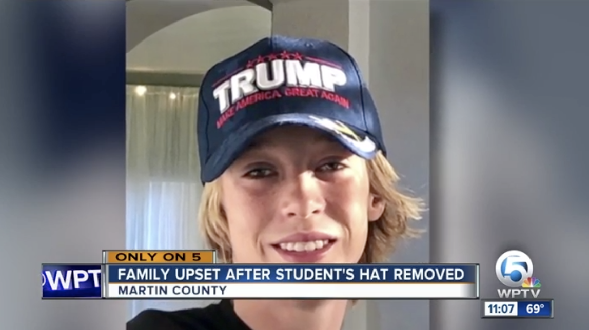 School bus aide takes student’s MAGA hat off of his head. (Photo: WPTV)