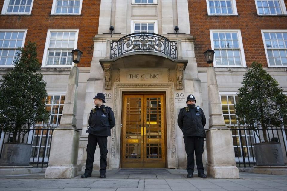 Two police officers standing guard outside a building labeled "THE CLINIC."