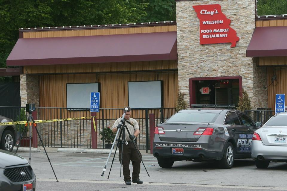 A St. Louis County crime scene investigator sets up cameras in front of Clay's Wellston Food Market Restaurant on Sunday, June 23, 2019, in Wellston, Mo., at the scene where a North County Cooperative police officer was shot inside the market. (J.B. Forbes//St. Louis Post-Dispatch via AP)