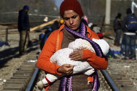 A stranded migrant holds a baby as she waits next to the Greek-Macedonian border near to the Greek village of Idomeni, November 30, 2015. REUTERS/Alexandros Avramidis