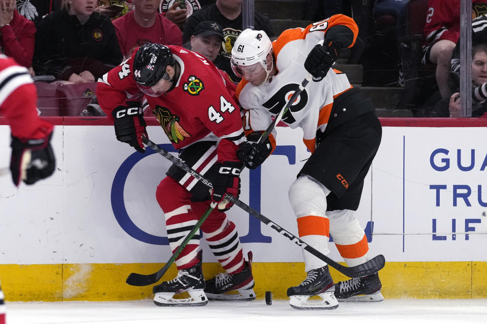 Chicago Blackhawks defenseman Wyatt Kaiser, left, and Philadelphia Flyers defenseman Justin Braun battle for the puck during the second period of an NHL hockey game in Chicago, Thursday, April 13, 2023. (AP Photo/Nam Y. Huh)