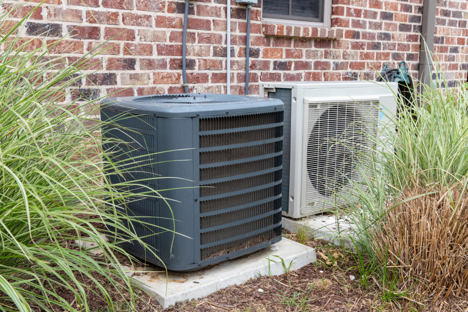 HVAC Air Conditioner Compressor and a Mini-split system together next to each other, next to a brick home.