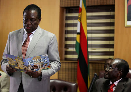 FILE PHOTO: Zimbabwe's President Robert Mugabe (R) looks on as his deputy Emmerson Mnangagwa reads a card during Mugabe's 93rd birthday celebrations in Harare, Zimbabwe, February 21, 2017. REUTERS/Philimon Bulawayo/File Photo