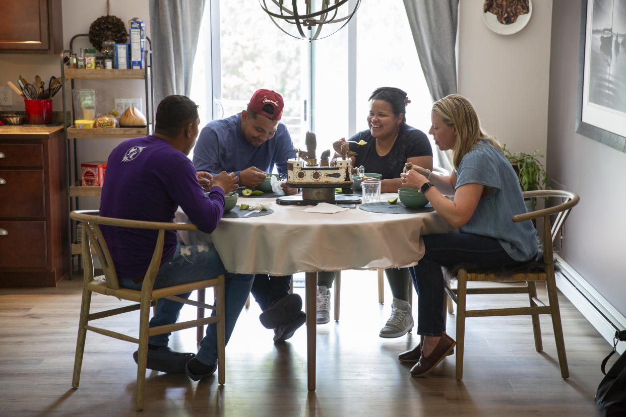 Desde la izquierda, Eliud Aguilar, Daniel Cauro y Deici Cauro, venezolanos, almuerzan con Rachel Self, abogada de inmigración, en la casa que han alquilado en Martha’s Vineyard. (Matt Cosby/The New York Times)