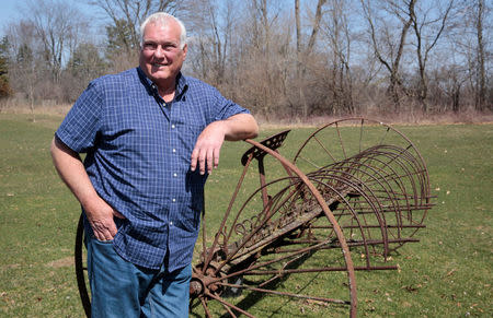Michigan resident Jerry Smith poses for a picture on his family farm next to a 'dump rake' once used by his grandfather, as he talks about voting and the U.S. presidential election, in Dexter, Michigan, U.S., April 12, 2018. Picture taken April 12, 2018. REUTERS/Rebecca Cook