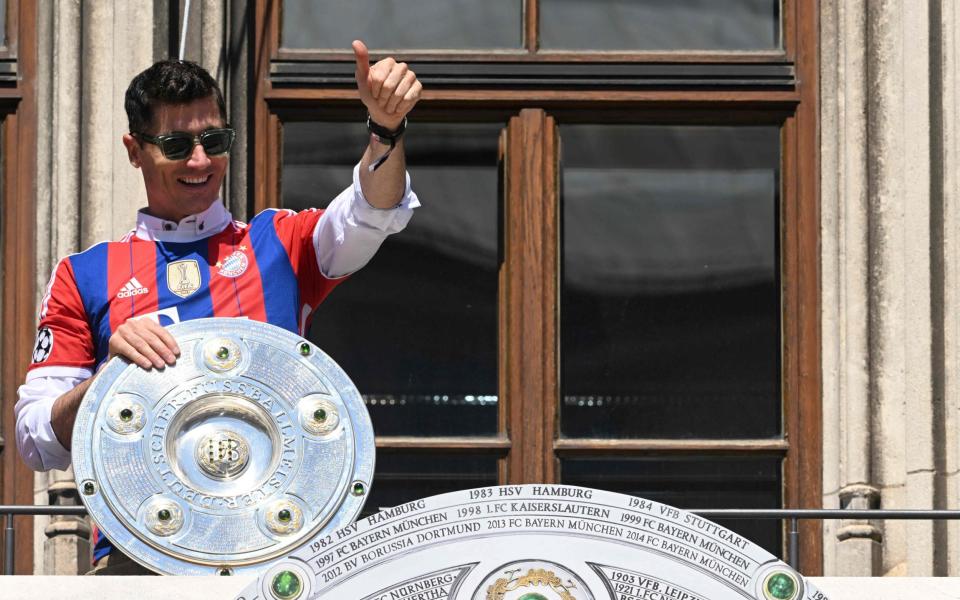 Bayern Munich's Polish forward Robert Lewandowski reacts from a balcony with the trophy of the Bundesliga season victory in the center of Munich - CHRISTOF STACHE/AFP