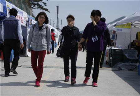 A woman (R) wears a picture of her daughter, a missing passenger on the capsized South Korean ferry Sewol, as she walks at a port in Jindo, where family members of missing passengers are gathered, April 22, 2014. REUTERS/Issei Kato