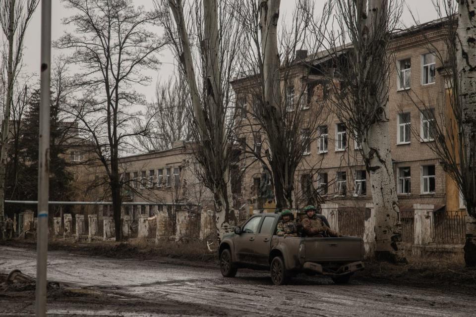 Ukrainian soldiers driving past a damaged building in Chasiv Yar, Donetsk Oblast, on March 16, 2024. A front line is a few kilometers from the city, on which Russian troops are dropping aerial bombs and shelling with artillery every day. Despite the danger, civilians remain in Chasiv Yar. (Roman Chop/Global Images Ukraine via Getty Images )