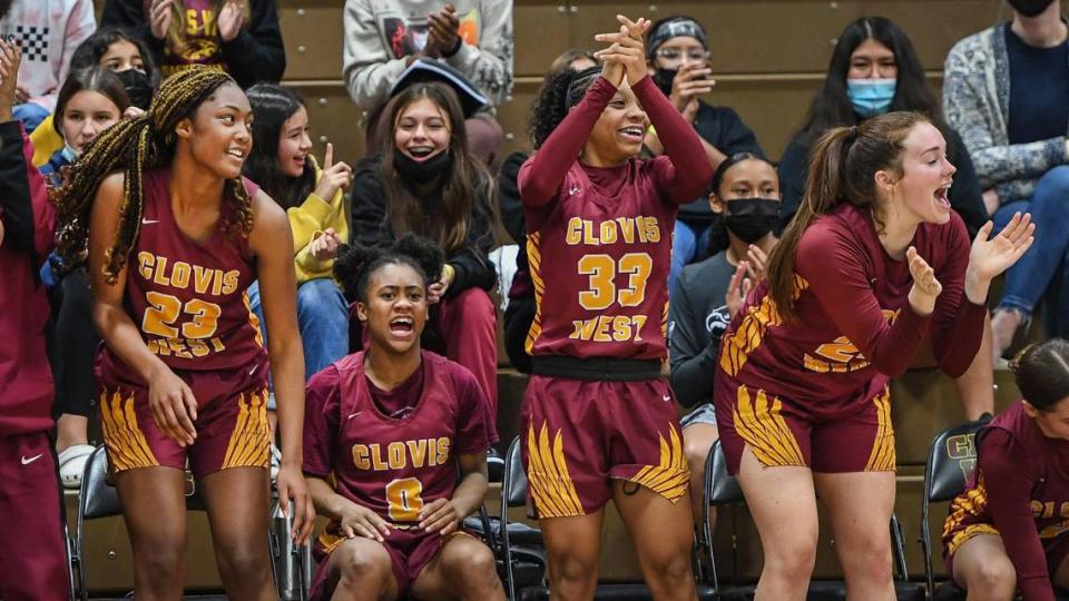 Clovis West’s Etoyah Montgomery, from left, Athena Tomlinson, Michaela Young, and Kennedy Vincent cheer on the Golden Eagles while subbing out late in the game against Heritage during the annual Nike Central Valley Showdown girls basketball tournament at Clovis West High School on Friday, Dec. 3, 2021.