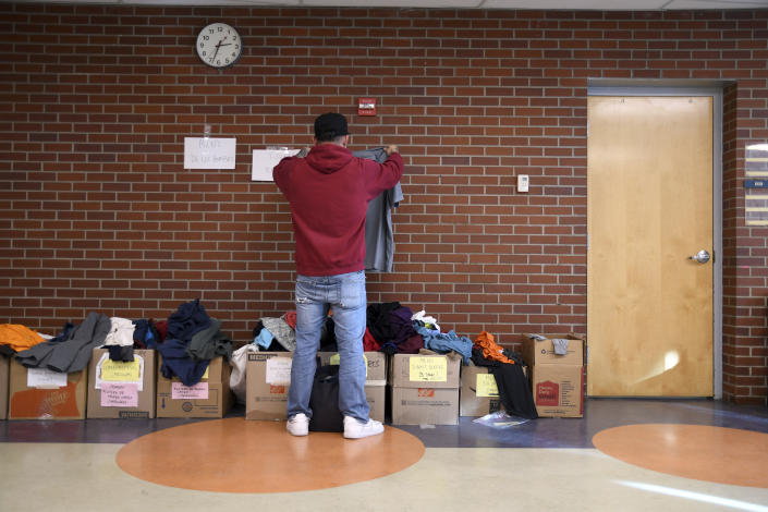 A migrant looks through donated clothes at a makeshift shelter in Denver, Friday, Jan. 6, 2023. Over the past month, nearly 4,000 immigrants, almost all Venezuelans, have arrived unannounced in the frigid city, with nowhere to stay and sometimes wearing T-shirts and flip-flops. In response, Denver converted three recreation centers into emergency shelters for migrants and paid for families with children to stay at hotels, allocating $3 million to deal with the influx. (AP Photo/Thomas Peipert)