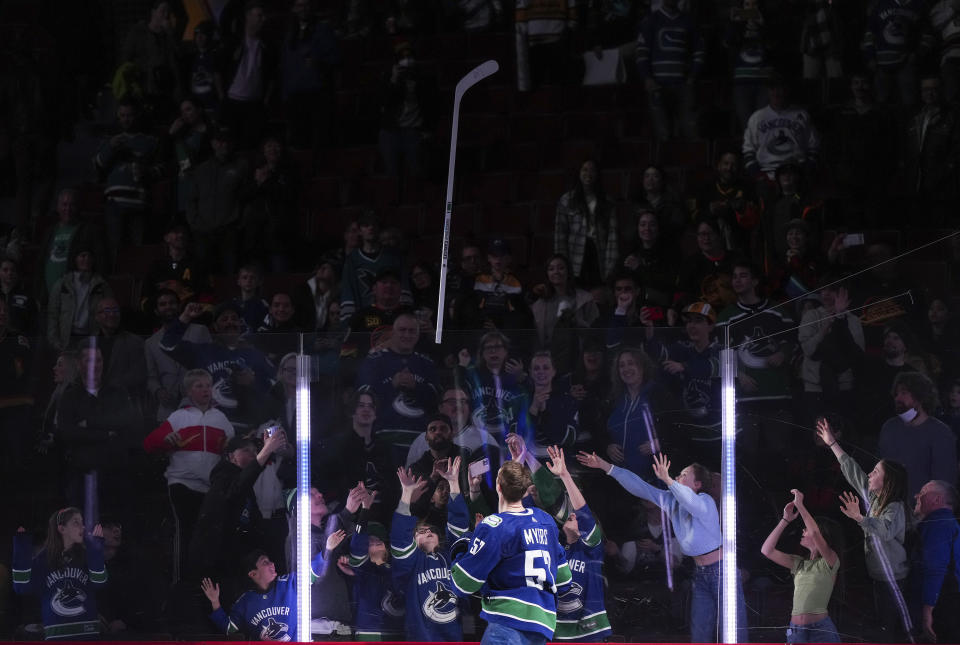 A group of kids reach for a stick tossed into the crowd by Vancouver Canucks' Tyler Myers after he was named the first star, after an NHL hockey game against the San Jose Sharks, in Vancouver, British Columbia, Thursday, March 23, 2023. (Darryl Dyck/The Canadian Press via AP)