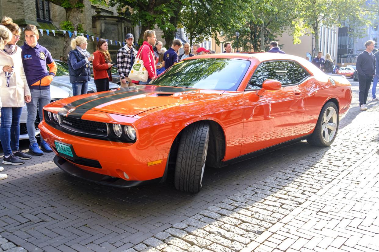 Dodge Challenger SRT American muscle car parked in a square in the city of Zwolle during a sunny summer morning. People in the background are looking at the cars.