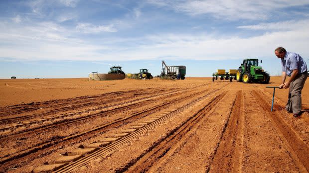 A farmer inspects the soil ahead of planting at a maize field in Wesselsbron, a small maize farming town in the Free State province of South Africa