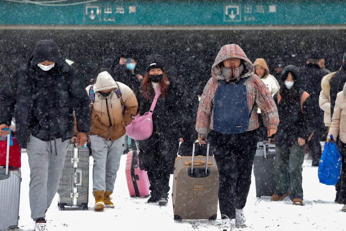 Travellers with their luggage walk in the snow as they exit a railway station in Huaibei, in central China’s Anhui province (AP)
