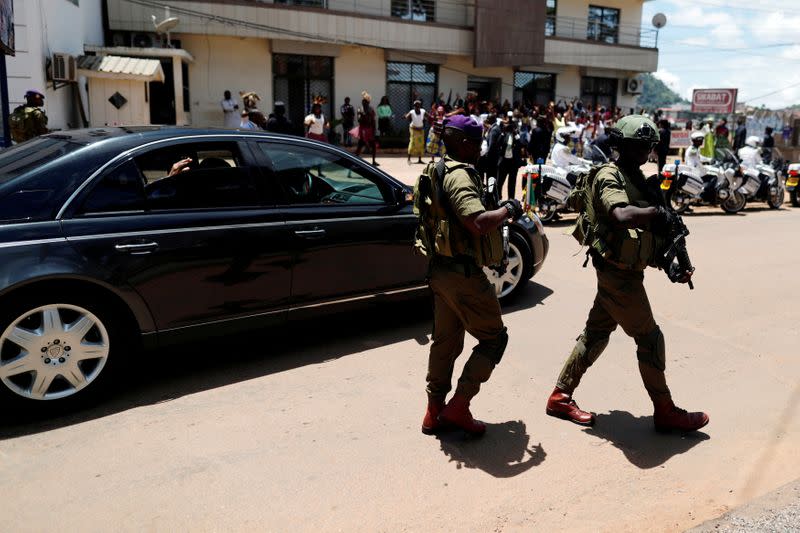 FILE PHOTO: Security guard walks beside the car of Cameroonian president Paul Biya as he leaves after casting his ballot during the presidential election, in Yaounde