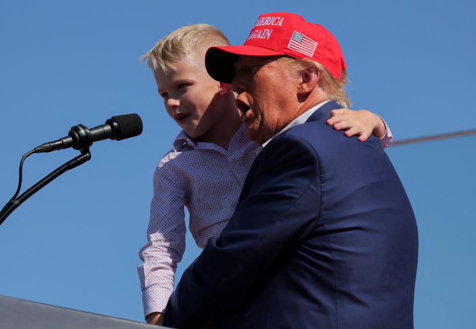 Trump holds his grandson, Luke Trump, up to the microphone at his Wilmington, North Carolina rally. Trump brought both Luke and Carolina, the children of Lara and Eric Trump, on stage (REUTERS)