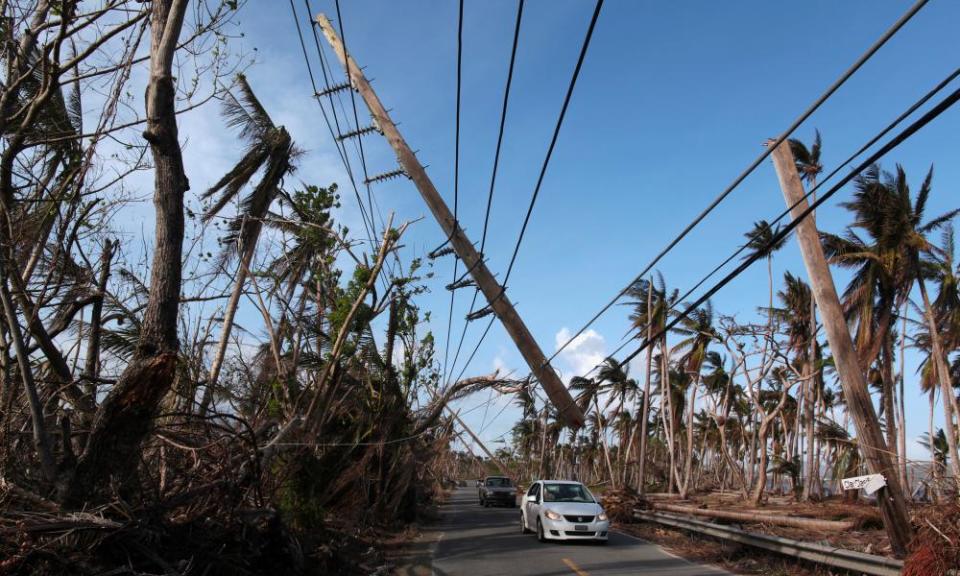 Cars drive under a partially collapsed utility pole in Puerto Rico. Nearly three quarters of the island is without electricity. 